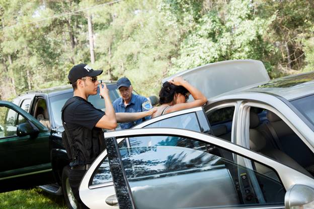 A photo shows a woman being searched by two police officers. The scene likely relates to the article about when police suspect weapons or drugs.